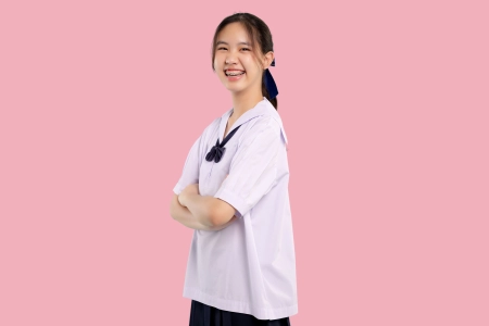 Happy braces asian student girl in school uniform arm crossed on isolated pastel background